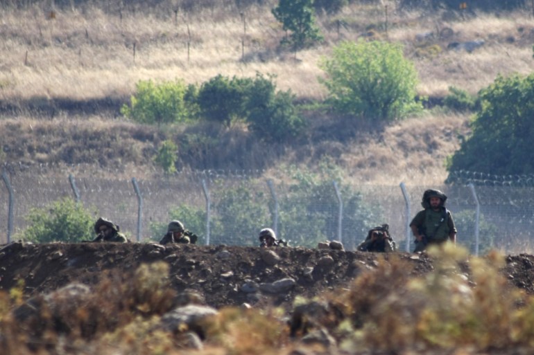 Israeli soldiers take positions near the border between Syria and the Israeli-occupied Golan Heights, as seen from the Syrian village of Beer Ajam, in the Quneitra Governorate, July 10, 2016. Picture taken July 10, 2016. REUTERS/Alaa Al-Faqir