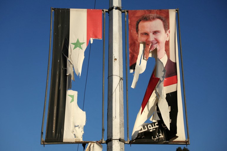 A billboard bearing a picture of Syria's President Bashar al-Assad and a national flag are torn by anti-government fighters in the northern city of Aleppo on November 30, 2024. - Jihadists and their Turkish-backed allies breached Syria's second city of Aleppo on November 29, as they pressed a lightning offensive against forces of the Iranian- and Russian-backed government. (Photo by Omar HAJ KADOUR / AFP)