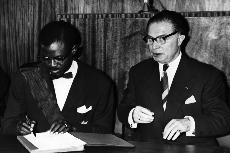 Lumumba signs the act of independence of the Congo in Leopoldville, Congo on June 30, 1960. At his right is Gaston Eyskens, the Belgian prime minister, who signed the act on behalf of Belgium. The Congo had been administered by Belgium for nearly 80 years [File: Jean-Jacques Levy/AP Photo]