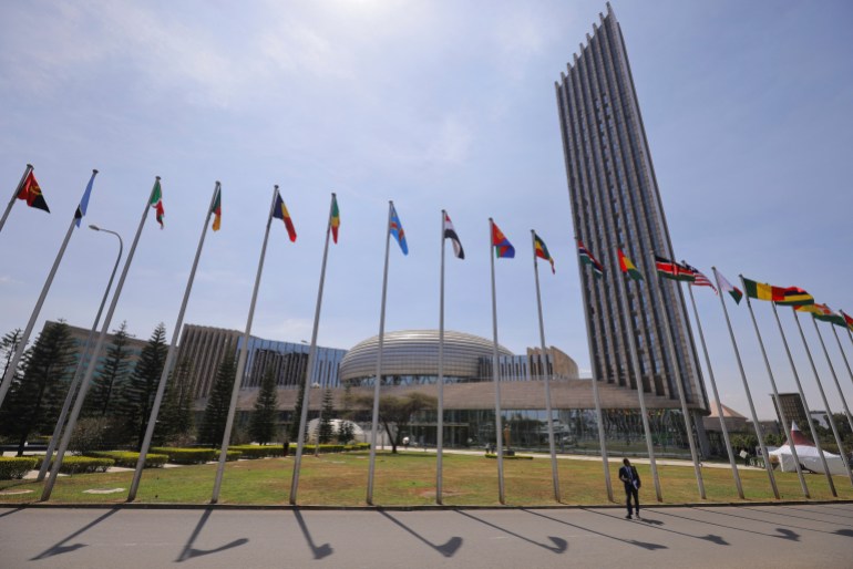 A delegate walks next to African Union (AU) member states flags ahead of the 38th Ordinary Session of the Heads of State and Government of the African Union at the African Union Commission (AUC) headquarters in Addis Ababa, Ethiopia, February 14, 2025. REUTERS/ Tiksa Negeri