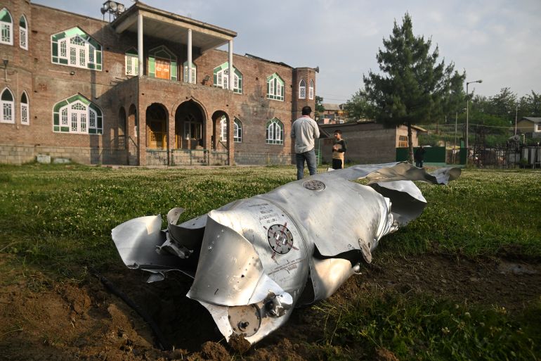 People stand near a part of an aircraft in Wuyan near Indian-administered Kashmir's main city of Srinagar on May 7, 2025.