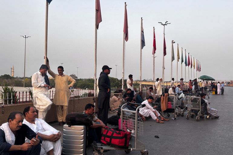 Passengers wait outside at Jinnah International airport after all domestic and international flights were cancelled in Karachi on May 7, 2025.