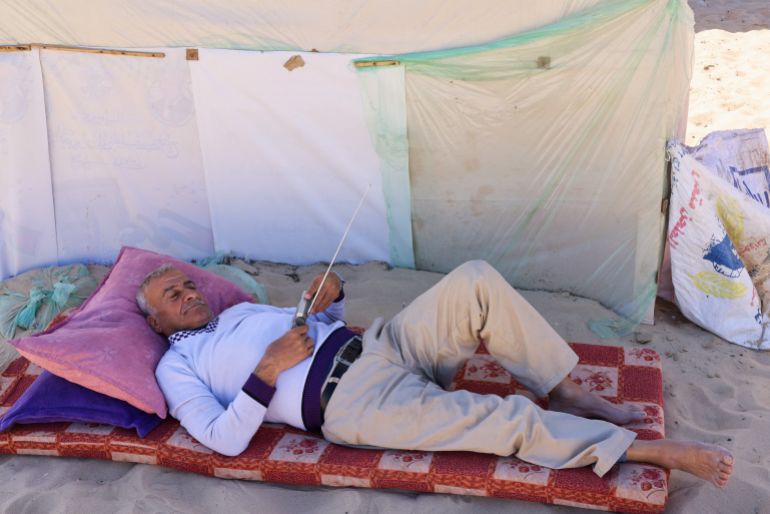 A displaced Palestinian, who fled his house due to Israeli strikes, lies down as he uses a radio to listen to the news at a tent camp, amid the ongoing conflict between Israel and the Palestinian Islamist group Hamas, in Rafah in the southern Gaza Strip, February 29, 2024. REUTERS/Saleh Salem