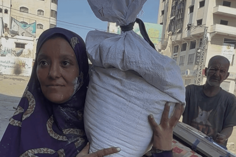 سيدة حامل تحمل على كتفها كيس من الدقيق، وهو كل ما استطاعت حمله خلال نزوحها القسري من منطقة أبو سكندر في حي الشيخ رضوان، شمال مدينة غزة المصدر: الجزيرة نت